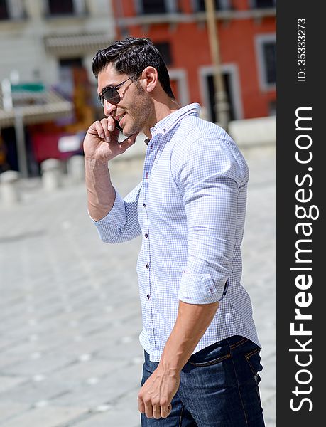 Portrait of good looking man in urban background talking on phone. Portrait of good looking man in urban background talking on phone