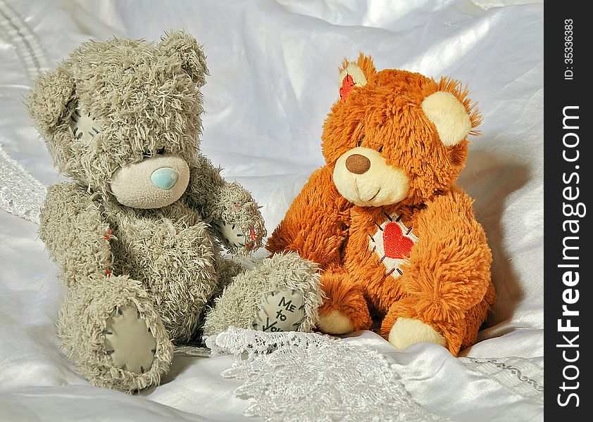 Toys gray and brown bears on the beautiful white linen in the bedroom. Toys gray and brown bears on the beautiful white linen in the bedroom