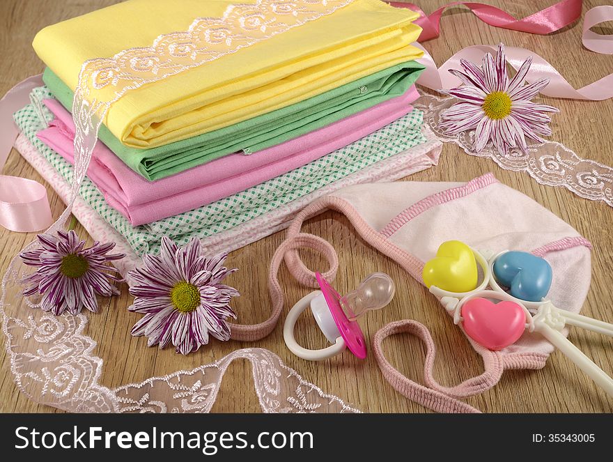 Baby still life of baby linen and small hat with flowers and playthings. Baby still life of baby linen and small hat with flowers and playthings