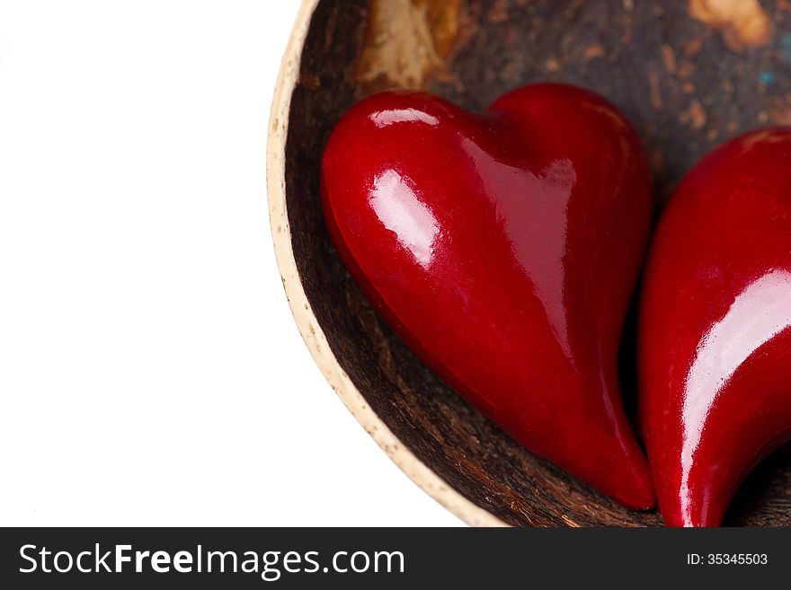 Two red hearts in a bowl of coconut, close-up, isolated on white