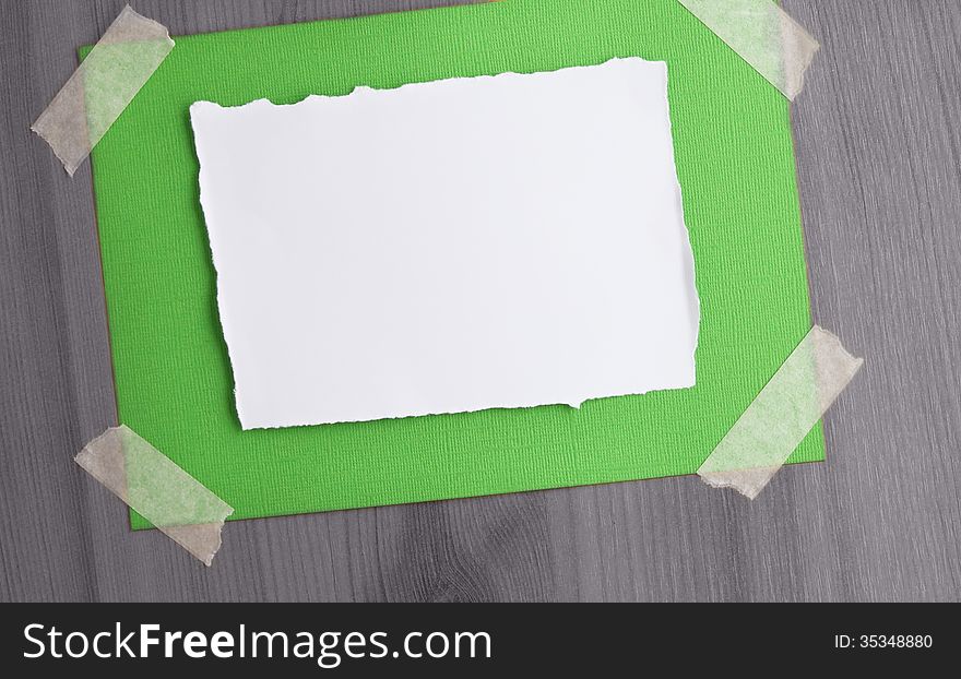A white paper on a canvas textured paper taped on a black and white wood background. A white paper on a canvas textured paper taped on a black and white wood background