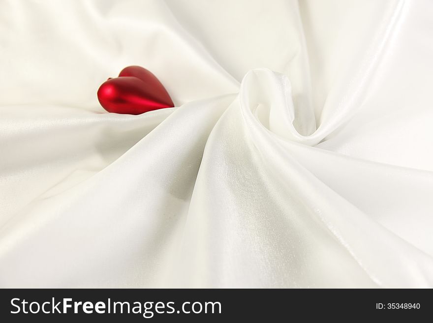 Image of twisted white shiny satin cloth with red heart on. Image of twisted white shiny satin cloth with red heart on