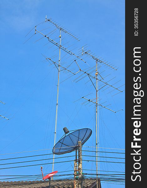 Satellite dish and Television antenna on roof with blue sky