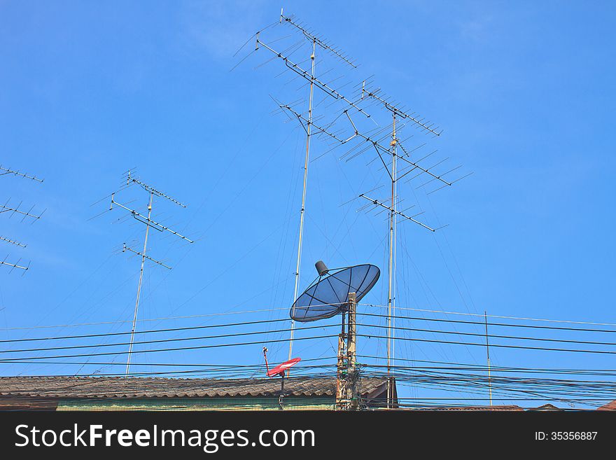 Satellite dish and Television antenna on roof with blue sky