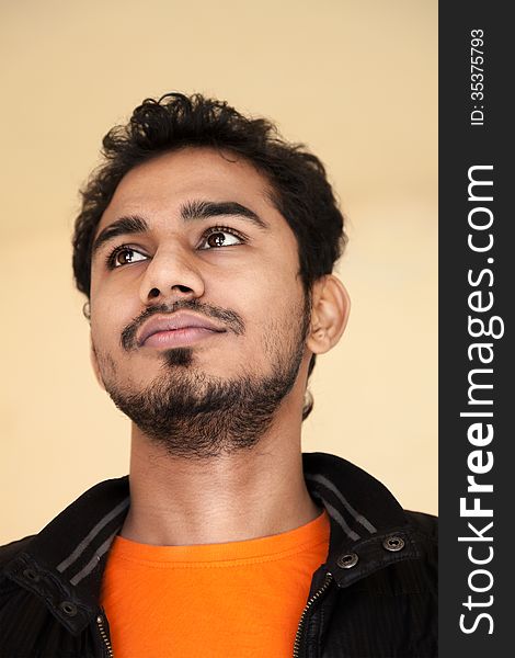 Indian young handsome man in thinking posture with black jacket and orange t-shirt. Indian young handsome man in thinking posture with black jacket and orange t-shirt