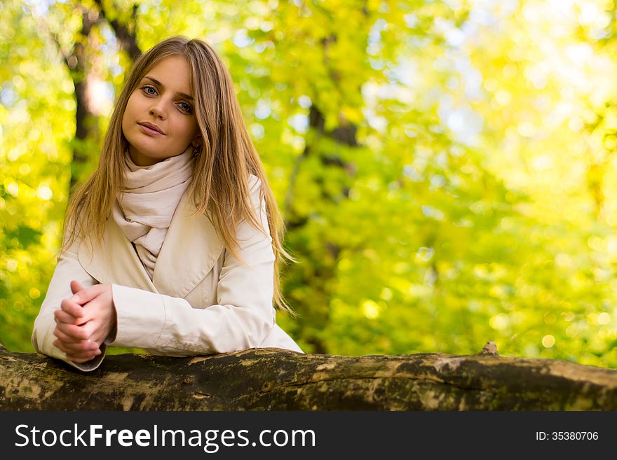 Portrait of a girl on a background autumn forest. A light raincoat. Black sweater. Portrait of a girl on a background autumn forest. A light raincoat. Black sweater.