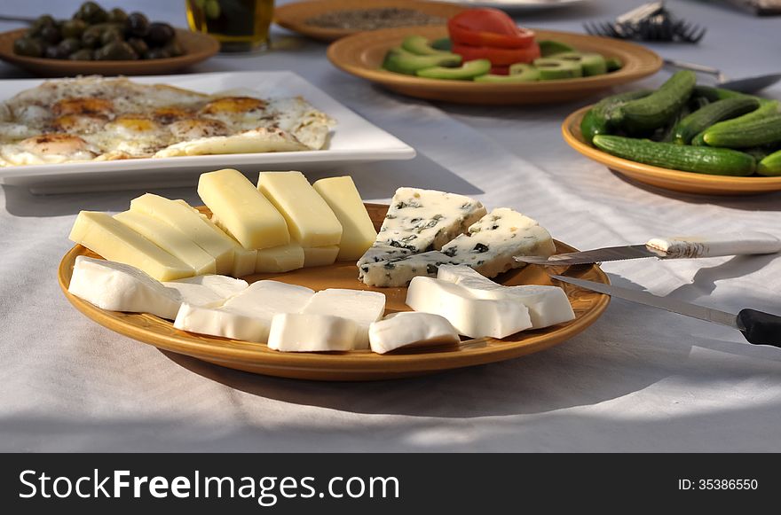Different types of cheese, sliced and displayed in a plate among other breakfast servings. Different types of cheese, sliced and displayed in a plate among other breakfast servings