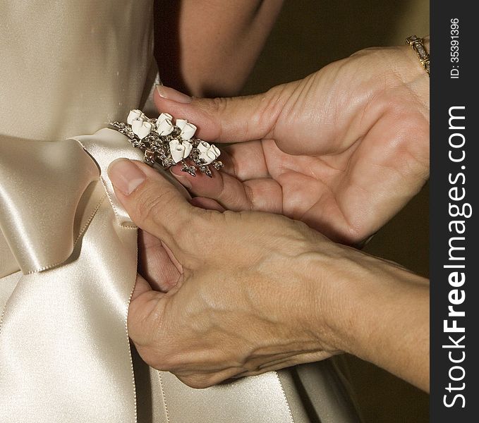 Mother of the bride pinning a broach on her daughters dress. Mother of the bride pinning a broach on her daughters dress