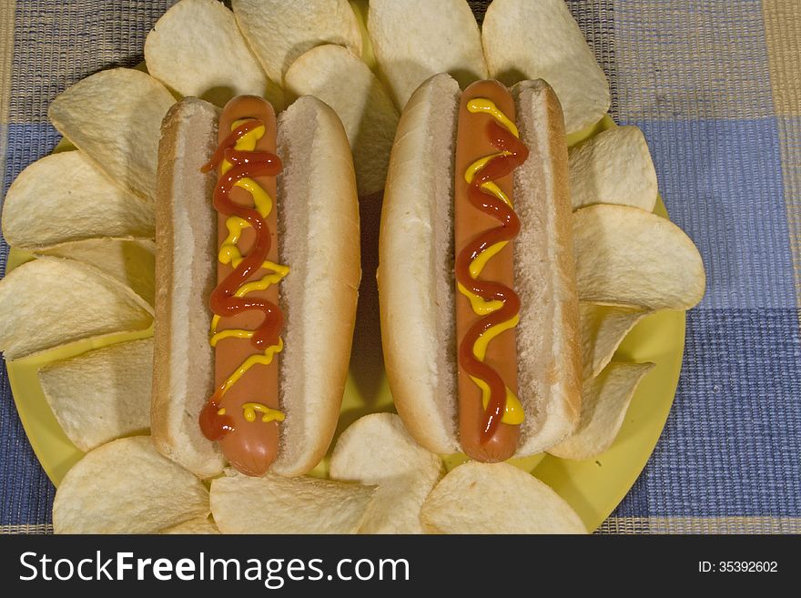 Hot dogs on a plate with chips