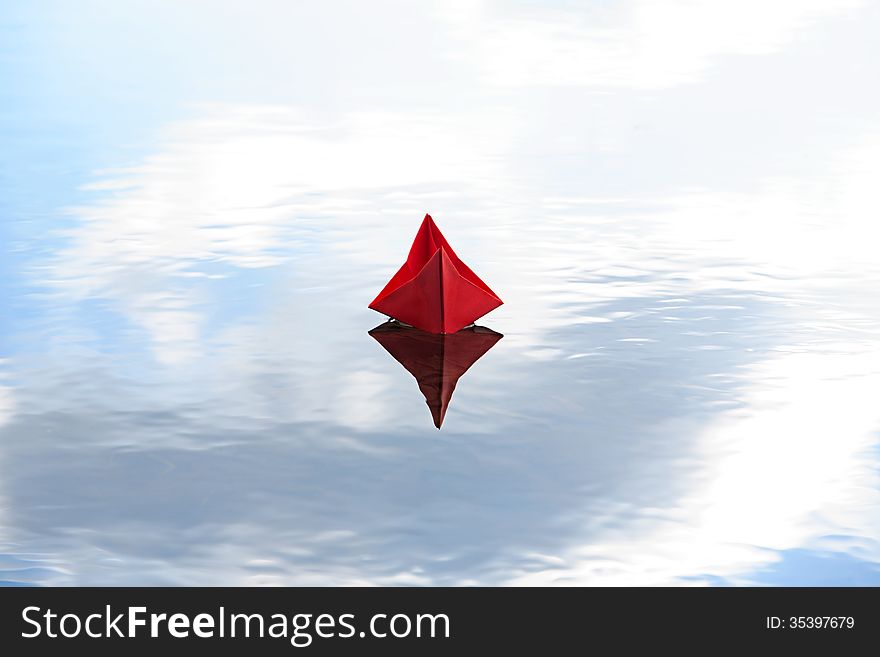 Red paper boat on blue water with free space for text
