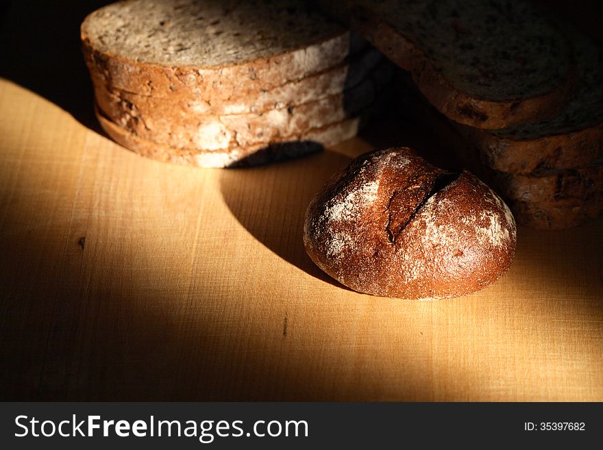 Set of bread on wooden board under beam of light