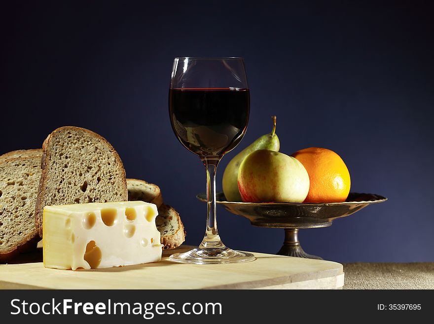 Still life with one goblet of red wine near sliced bread and cheese. Still life with one goblet of red wine near sliced bread and cheese