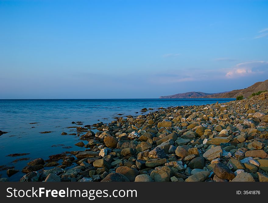 Stones on wild beach on mountains and sky background