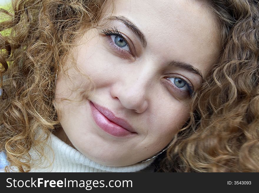 Face of smiling female with curling hair and green eyes. Face of smiling female with curling hair and green eyes