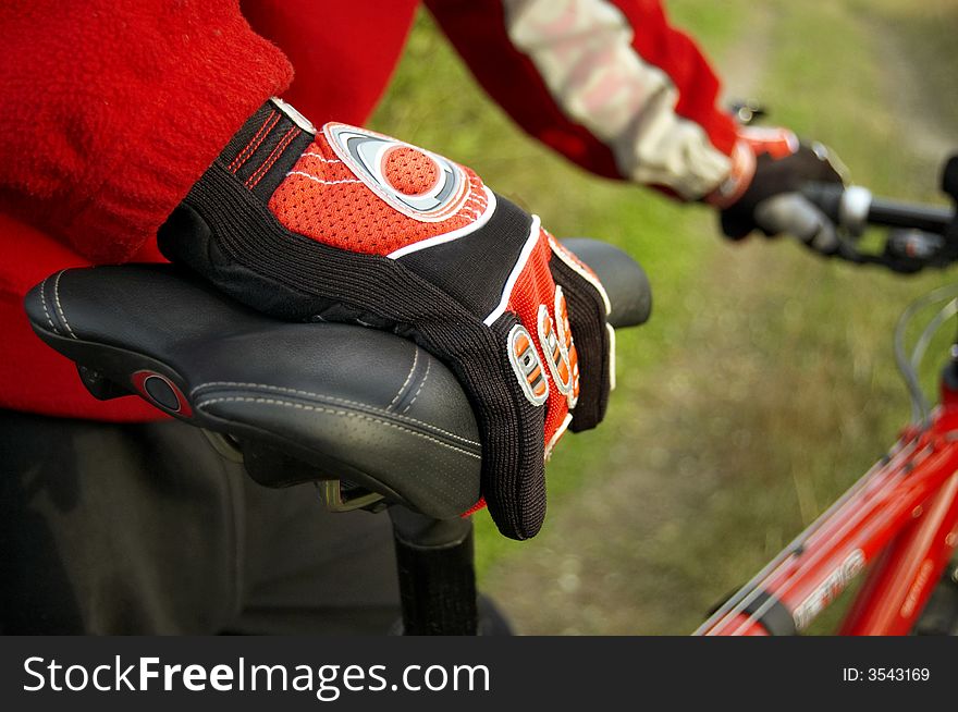 Spotrive gloves on a sportive red bike's seat. Spotrive gloves on a sportive red bike's seat