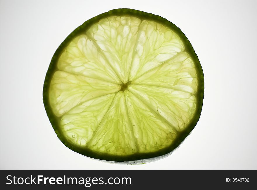 Lime slice, isolated and backlit with white backdrop