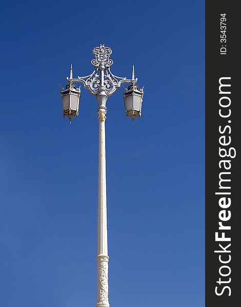 An old fashioned lamp post photographed against a bright blue sky