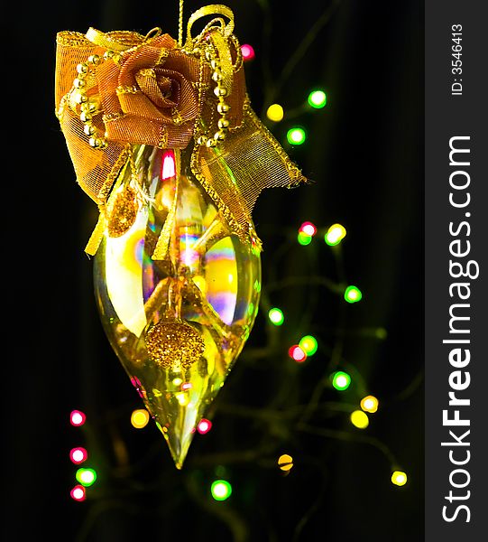 A refractive pointed ellipsoid ornamented with a fabric rose hung in mid air against a blur background of colored lights. A refractive pointed ellipsoid ornamented with a fabric rose hung in mid air against a blur background of colored lights.