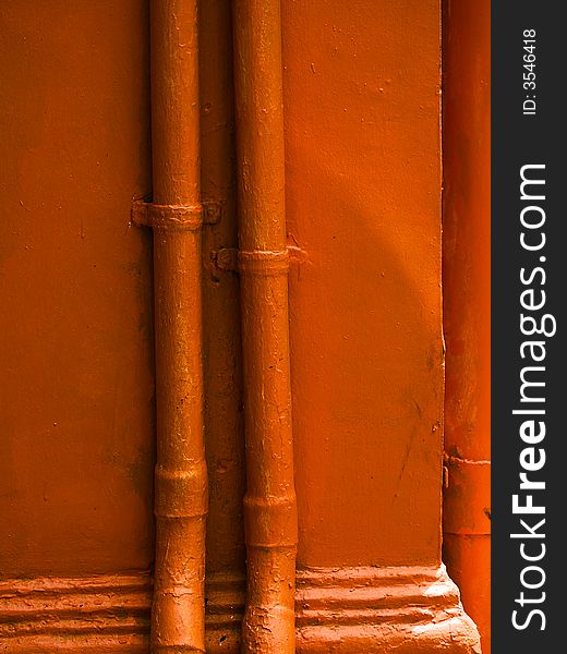 Orange Pipes running vertically up the sides of an orange coloured pillar