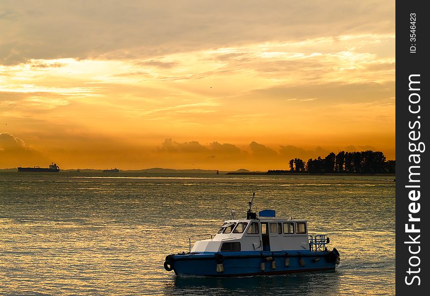 A harbour launch shuttling between the shore and a ship anchorage area in the morning. A harbour launch shuttling between the shore and a ship anchorage area in the morning