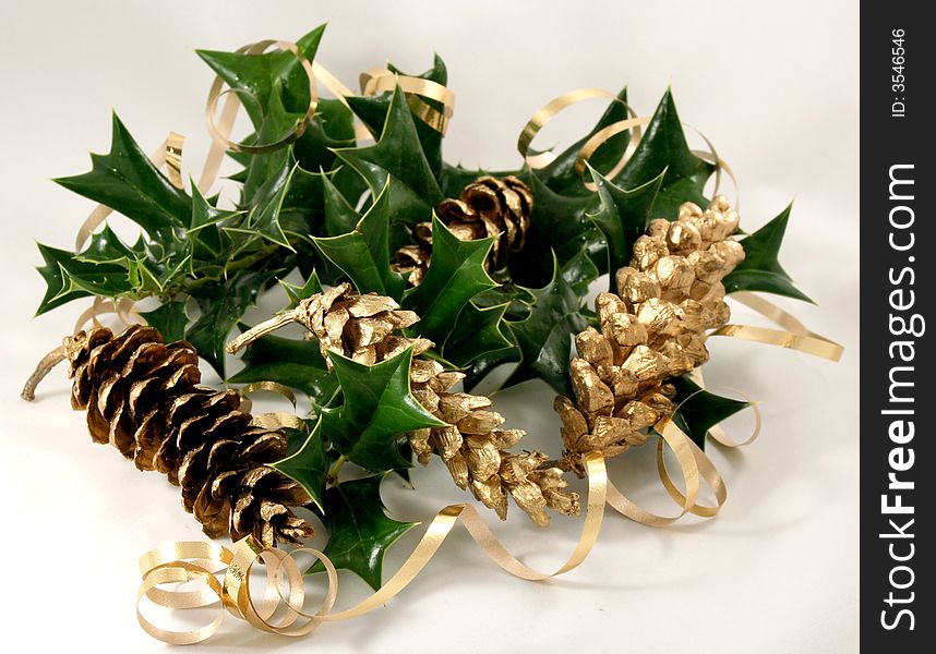 Holly leaves entwined with gold ribbon and gold pinecones. Holly leaves entwined with gold ribbon and gold pinecones.