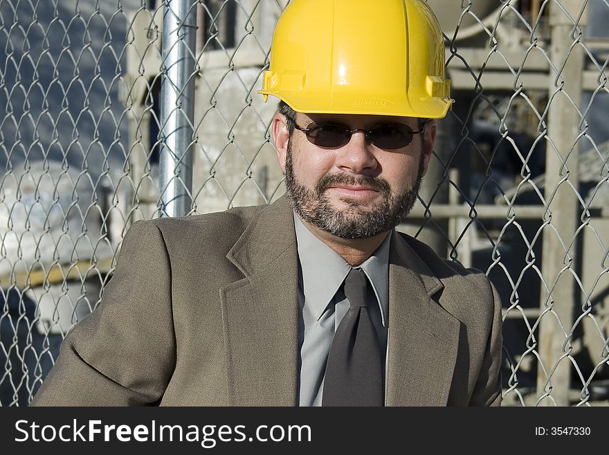 Man in suit at construction site  wearing yellow hardhat. Man in suit at construction site  wearing yellow hardhat.