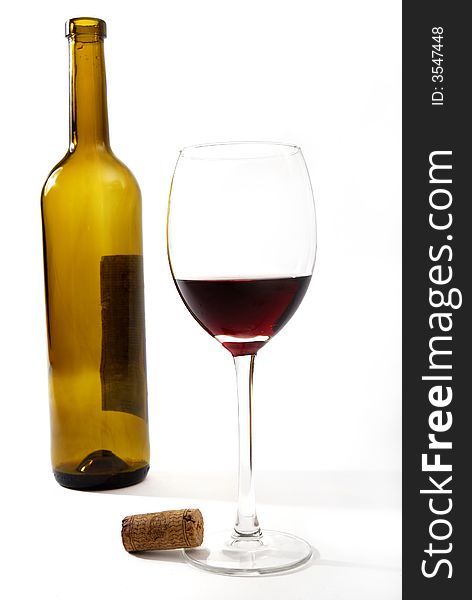 Red vine in a glass and a bottle in front of a white background