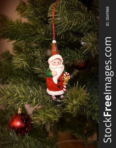 A santa decoration hanging in the christmas tree with other christmas decorations. A santa decoration hanging in the christmas tree with other christmas decorations