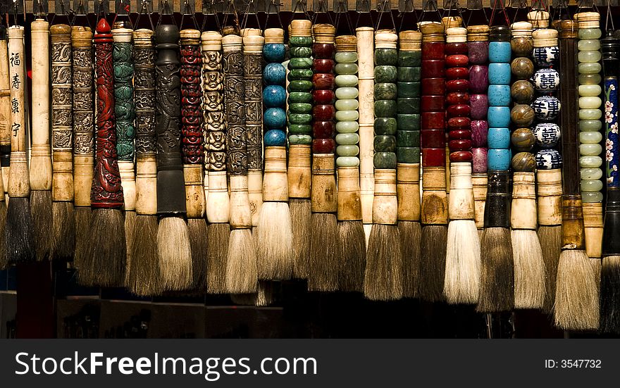 Chinese brushes in different colours hanging in a shop on a stand