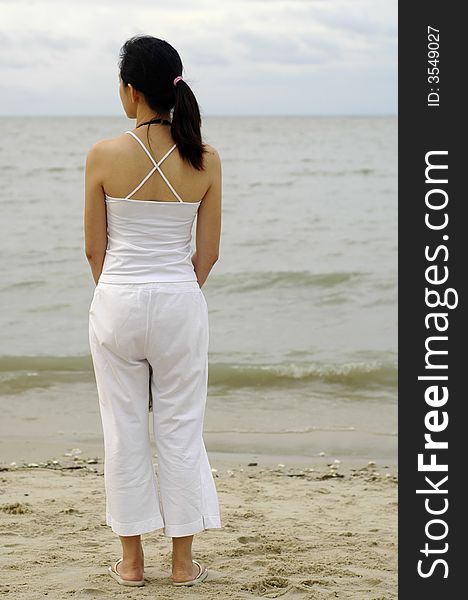 An Asian lady by the beach enjoying sea breeze. An Asian lady by the beach enjoying sea breeze.