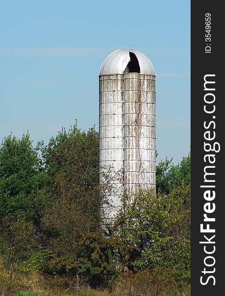 An old silo with trees against blue sky