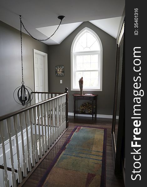 A Gothic window and large accent mirror are the focal points of a second floor hallway in a custom built residential home. A Gothic window and large accent mirror are the focal points of a second floor hallway in a custom built residential home