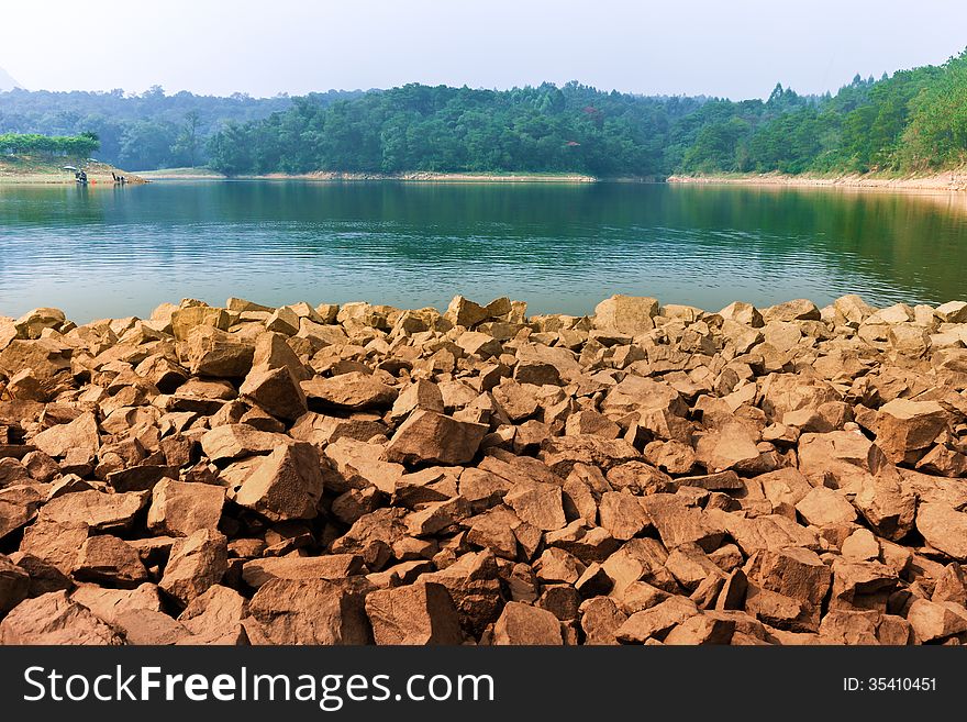 Natural lake in forest , rocky bank. Natural lake in forest , rocky bank