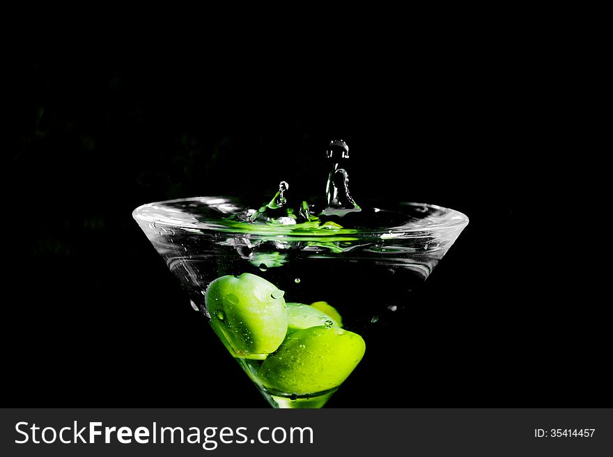 Close up o martini drink with green olives on black background