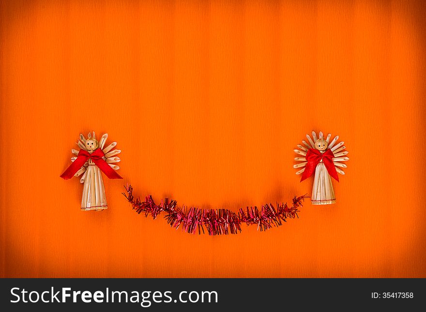 Orange Background for Christmas card with angels made â€‹â€‹of straw