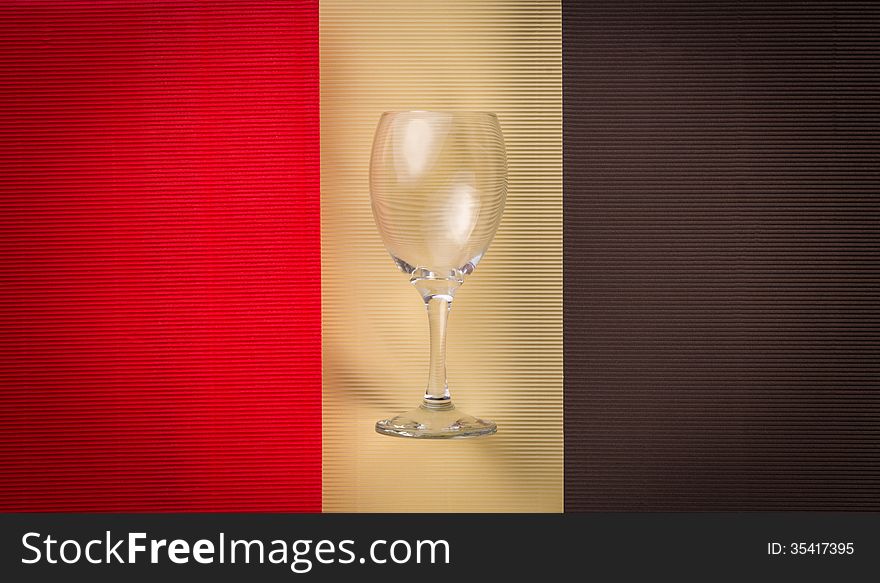 Empty glass over red, black and cream-color texture