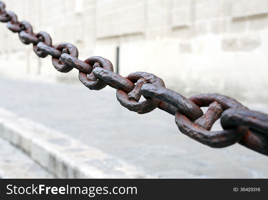 Old long rusty chain on gray building wall background. Old long rusty chain on gray building wall background