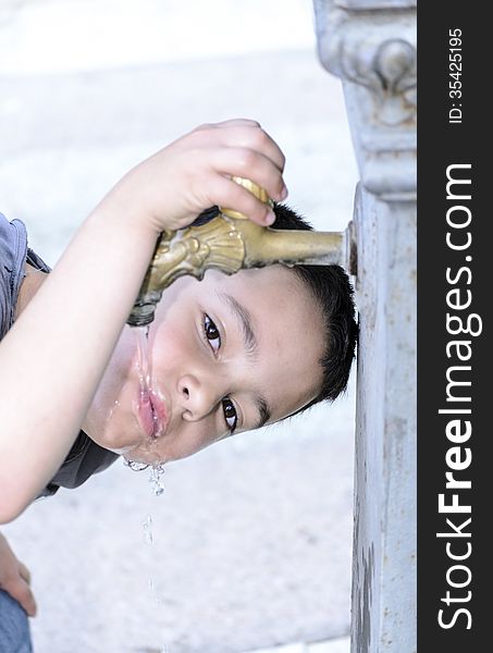 Child drinks water in a fountain in a park. Child drinks water in a fountain in a park.