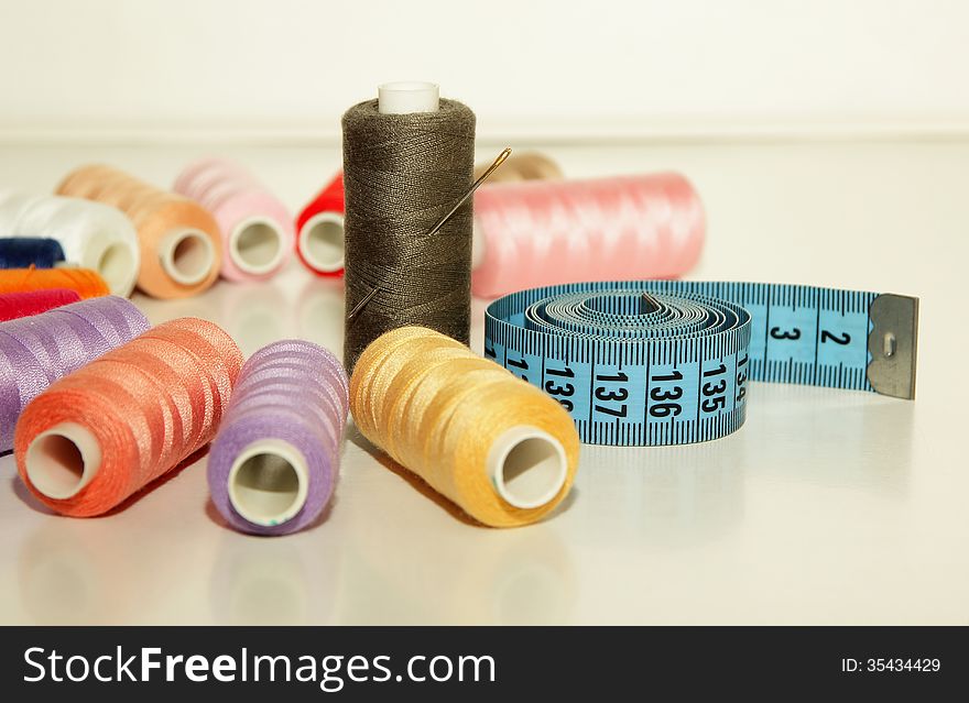 Colorful Spools Of Thread, A Needle To Inject Into The Coil And Measuring Tape