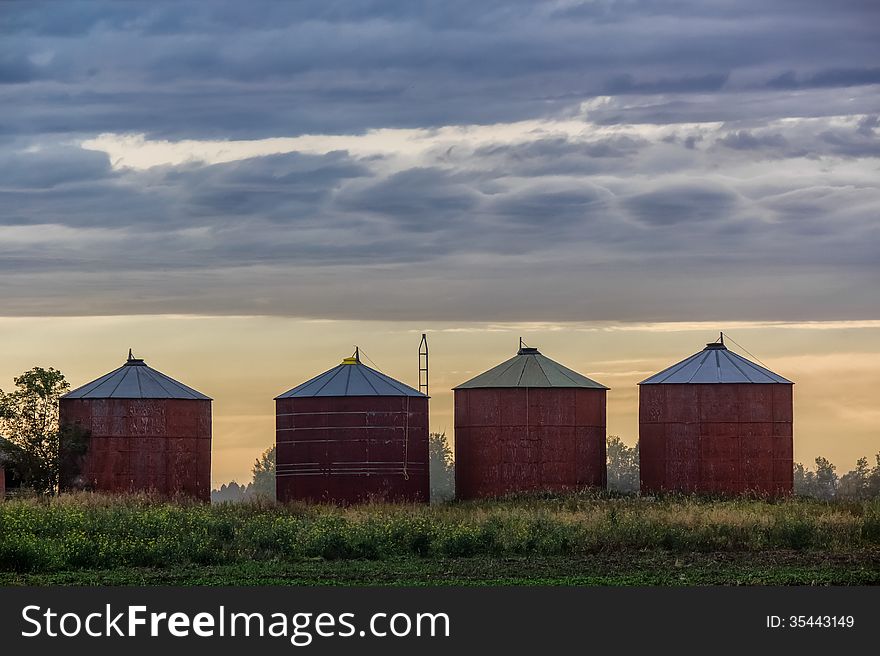 Grain bins against a setting sun