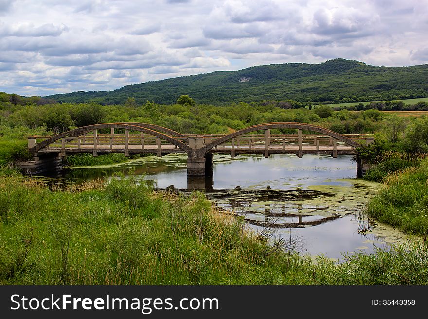 Concrete bridge over a river with surrounding hills