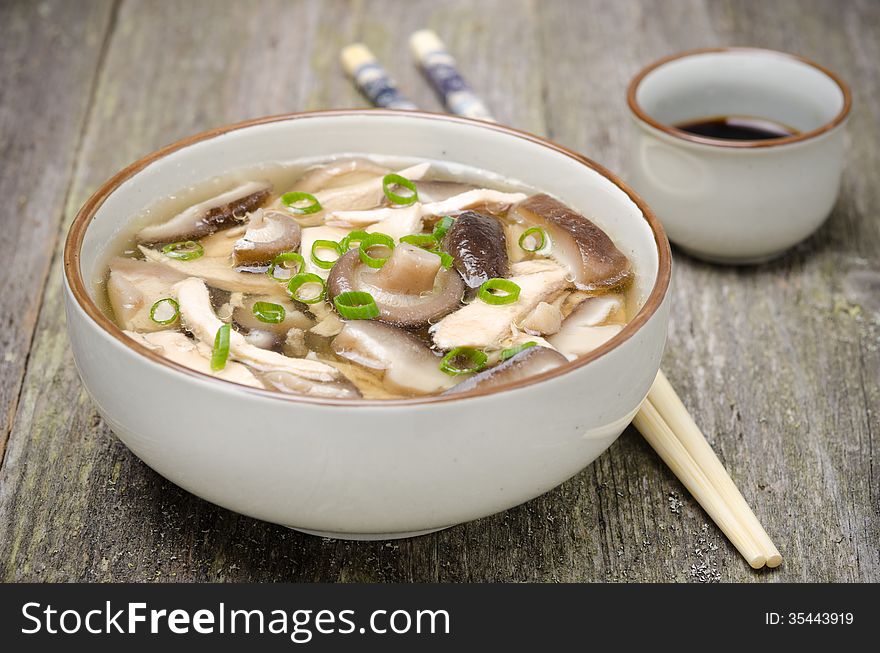 Chinese food - bowl of soup with chicken, shiitake mushrooms and green onions, soy sauce, close-up