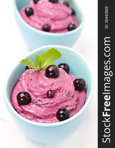 Close-up of black currant mousse with cream cheese in blue bowls, vertical