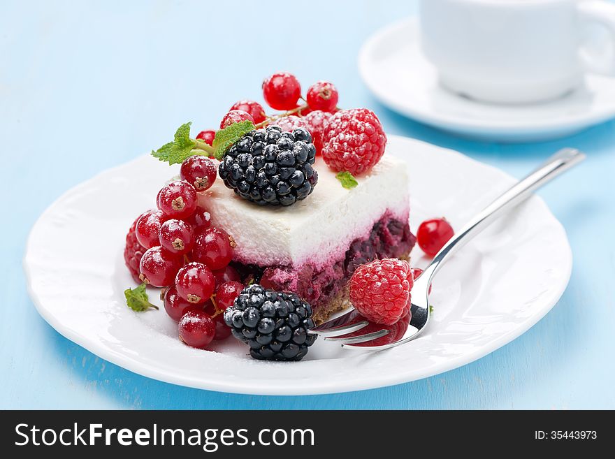 Dessert - a piece of cake with fresh berries on blue background, horizontal