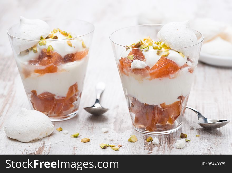 Dessert with canned peaches, whipped cream and meringue in a glasses, horizontal