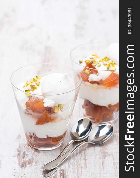 Dessert with peaches, whipped cream and meringue on white wooden table