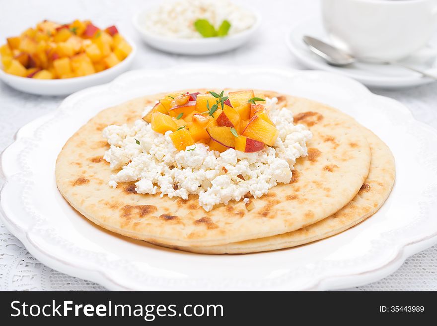 Flat bread with cottage cheese with honey, nuts, fresh peaches and thyme, close-up, horizontal