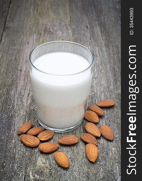 Glass of almond milk on a wooden table, vertical