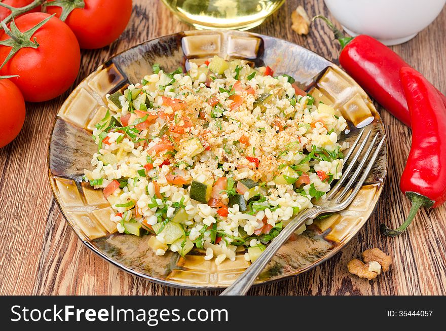 Salad with bulgur, zucchini, tomatoes, parsley on the plate on a wooden table