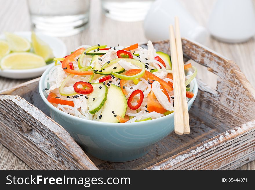 Thai salad with vegetables, rice noodles and chicken in a bowl
